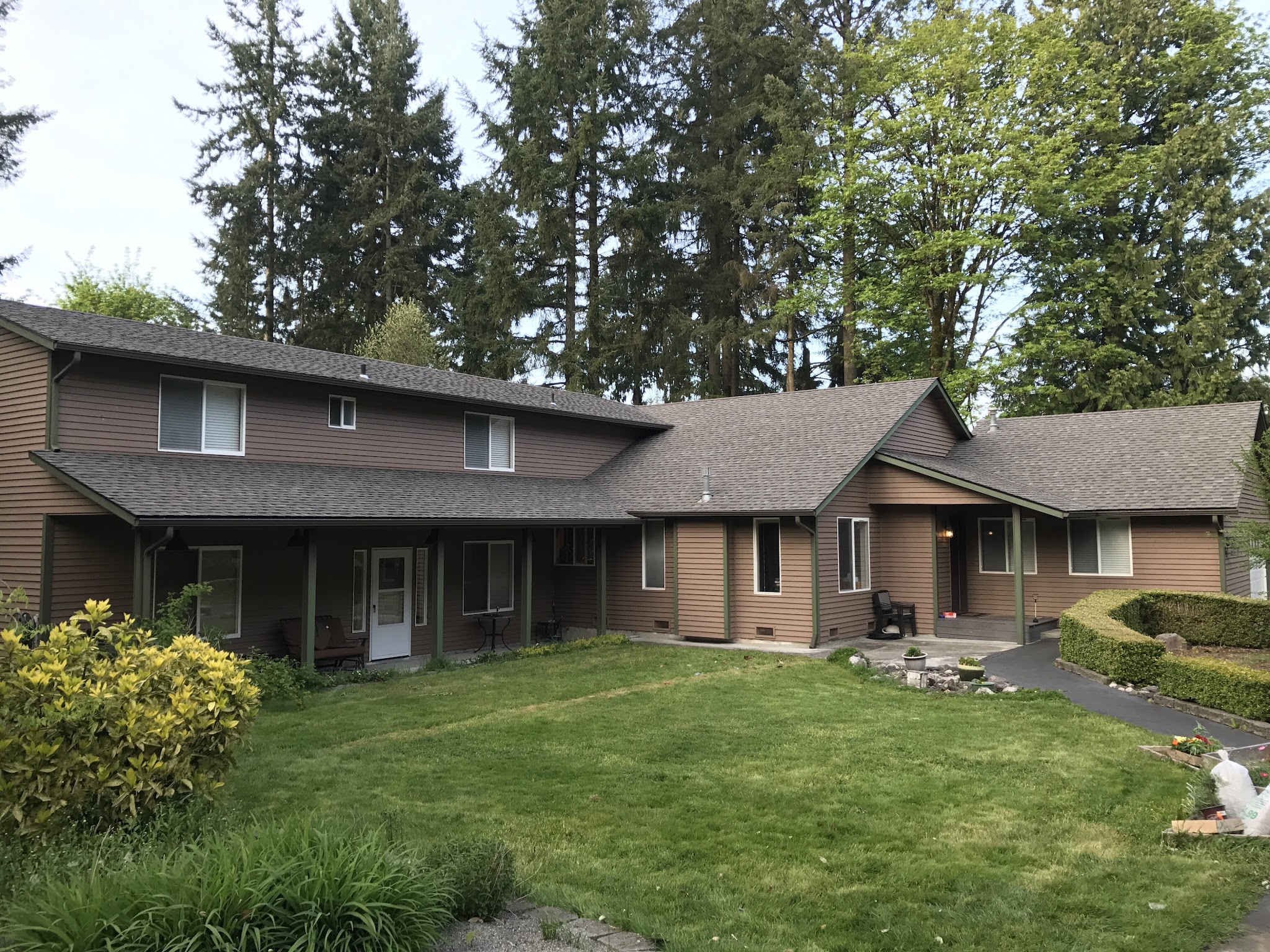Finished home exterior with new roof and siding on a forested lot